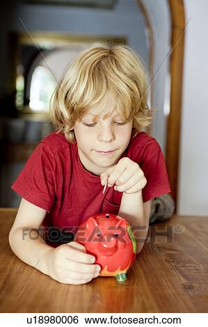 A boy putting money in a piggy bank View Large Photo Image Stock Photograph - A boy putting money in a piggy bank. Fotosearch