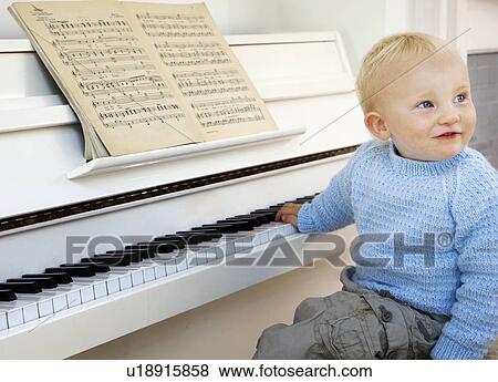Stock Photo - A boy toddler sitting at the piano. Fotosearch