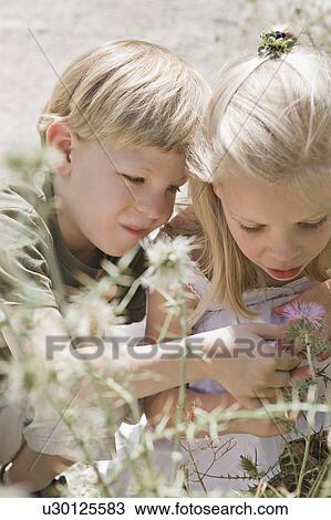 Stock Image - A brother and sister looking at a flower. Fotosearch