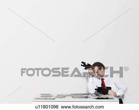 Stock Photo - A business man doing a jigsaw. Fotosearch