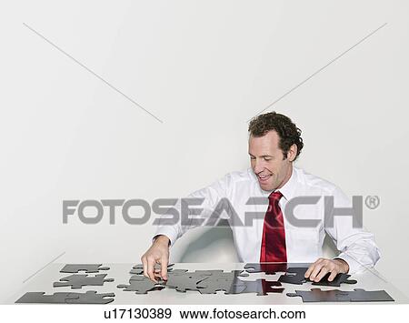 Stock Photo - A business man doing a jigsaw. Fotosearch