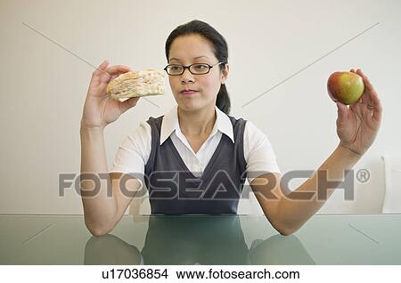 Picture - A business woman deciding what to eat. Fotosearch