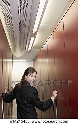 Stock Photography - A business woman in a store cupboard. Fotosearch