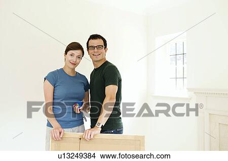 A couple putting up a picture. View Large Photo Image Picture - A couple putting up a picture.. Fotosearch