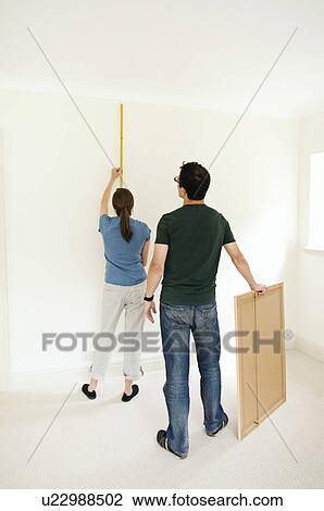 A couple putting up a picture. View Large Photo Image Stock Image - A couple putting up a picture.. Fotosearch