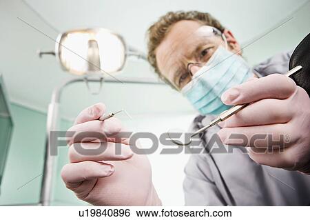 Stock Photograph - A dentist examining a patient. Fotosearch
