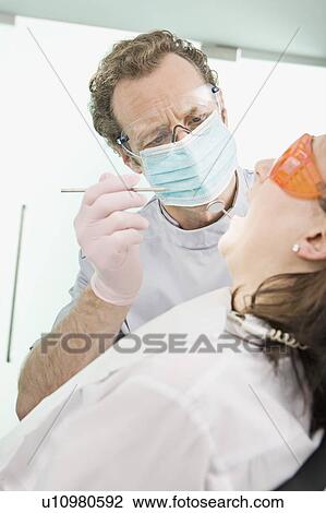 A dentist in surgery examining a patient View Large Photo Image Stock Image - A dentist in surgery examining a patient. Fotosearch