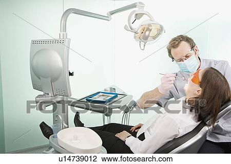 Stock Image - A dentist in surgery examining a patient. Fotosearch
