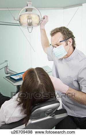 A dentist in surgery examining a patient View Large Photo Image Stock Photo - A dentist in surgery examining a patient. Fotosearch
