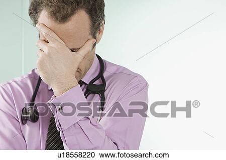 A doctor holding his hand over his face View Large Photo Image Stock Image - A doctor holding his hand over his face. Fotosearch