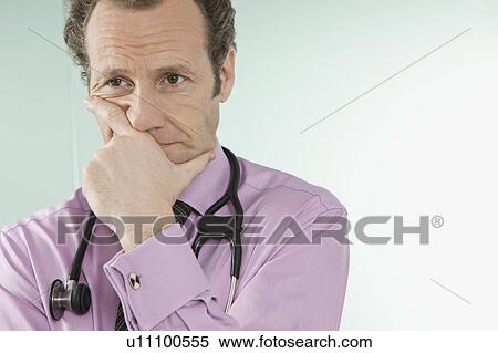 Stock Photography - A doctor holding his hand over his mouth. Fotosearch