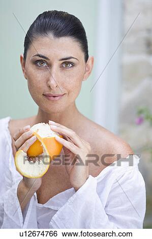 Stock Photograph - A female beauty peeling an orange. Fotosearch