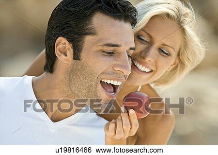 A female feeding a latin man an apple. View Large Photo Image Stock Photograph - A female feeding a latin man an apple.. Fotosearch