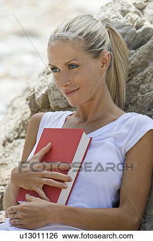 A female holding a book on the beach View Large Photo Image Stock Photograph - A female holding a book on the beach. Fotosearch