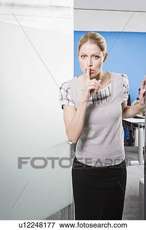 Stock Photo - A female saying 'Shhh' outside an office. Fotosearch