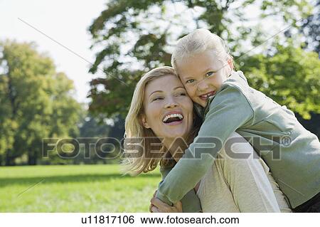 Stock Photograph - A girl having a piggy back from her mum. Fotosearch