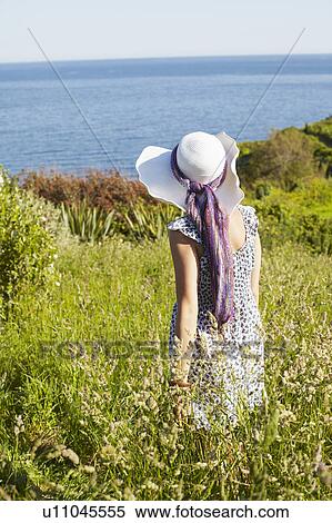 Stock Photography - A girl in a field looking at the sea. Fotosearch