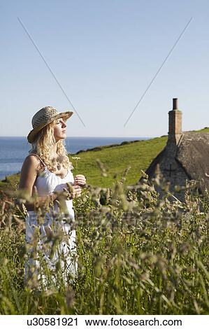 A girl in a field with a flower View Large Photo Image Stock Image - A girl in a field with a flower. Fotosearch