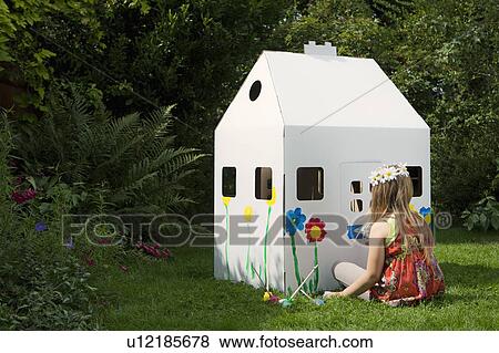 Stock Photo - A girl painting a cardboard wendy house. Fotosearch