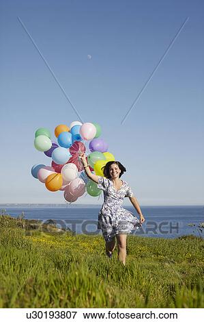 Stock Photo - A girl running with balloons. Fotosearch