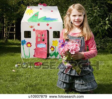 Stock Photo - A girl with flowers and a wendy house. Fotosearch