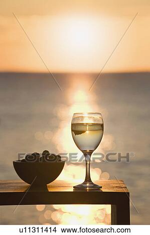 Picture - A glass of wine and olives at sunset. Fotosearch