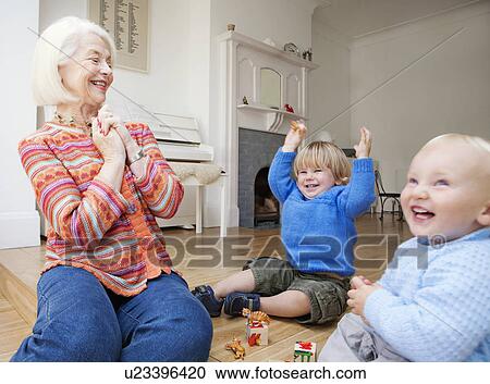 Stock Image - A grandmother playing with two toddlers. Fotosearch