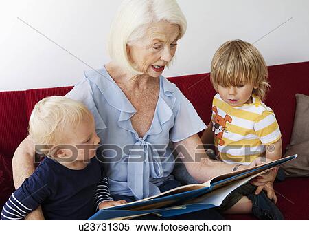 Stock Photography - A grandmother reading to two toddlers. Fotosearch
