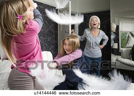 Stock Photograph - A granny shouts at girls pillow fighting. Fotosearch