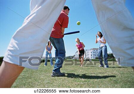 Stock Photography - A group playing baseball in a park. Fotosearch