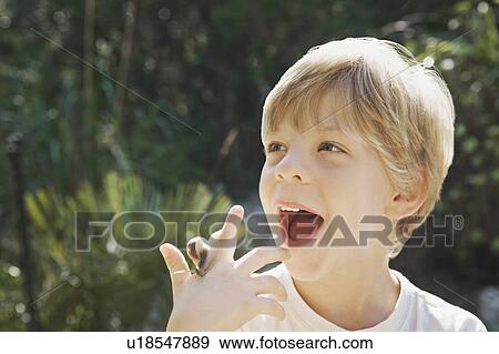 Stock Photo - A headshot of a boy with a snail. Fotosearch