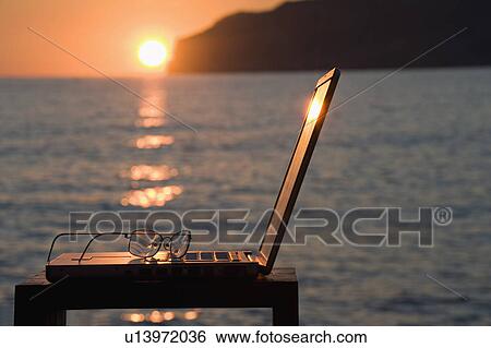 A laptop and reading glasses at sunset View Large Photo Image Stock Photograph - A laptop and reading glasses at sunset. Fotosearch