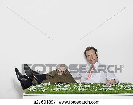 Stock Photo - A man sitting at a grassy desk. Fotosearch