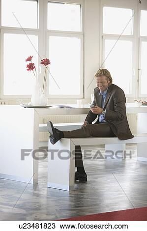 Stock Image - A Mid-40 Businessman sitting on a bench. Fotosearch