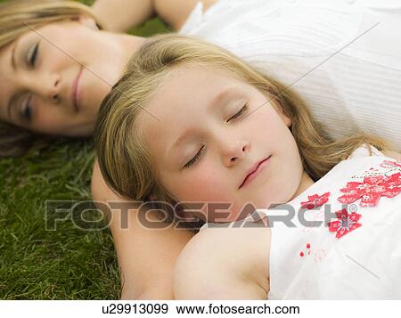 A mother and daughter lying on a lawn View Large Photo Image Stock Photo - A mother and daughter lying on a lawn. Fotosearch