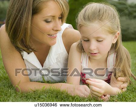 A mother and daughter lying on a lawn View Large Photo Image Stock Photograph - A mother and daughter lying on a lawn. Fotosearch