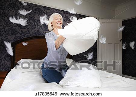 A senior female fluffs up a cushion View Large Photo Image Stock Photograph - A senior female fluffs up a cushion. Fotosearch