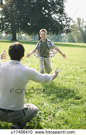 Stock Image - A son running to his daddy in the park.. Fotosearch