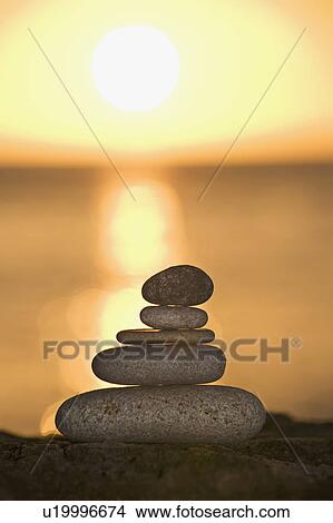 Picture - A stone stack against a setting sun. Fotosearch