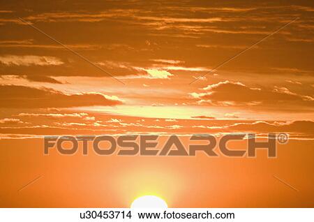 Picture - A sun setting against an orange sky. Fotosearch
