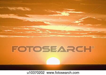 A sun setting against an orange sky View Large Photo Image Stock Image - A sun setting against an orange sky. Fotosearch