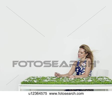 Stock Photography - A woman sitting at a grass covered desk. Fotosearch