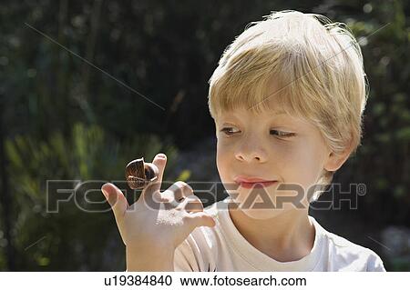 Stock Image - A young boy with a snail. Fotosearch