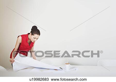 A young business woman looking at plans View Large Photo Image Stock Image - A young business woman looking at plans. Fotosearch