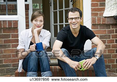 Stock Photograph - A young couple sitting on their doorstep. Fotosearch