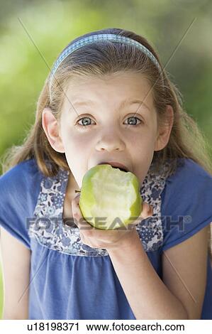 Stock Image - A young girl eating an apple. Fotosearch