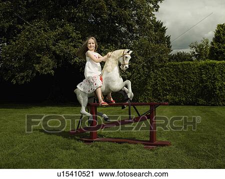 Stock Image - A young girl on a rocking horse. Fotosearch