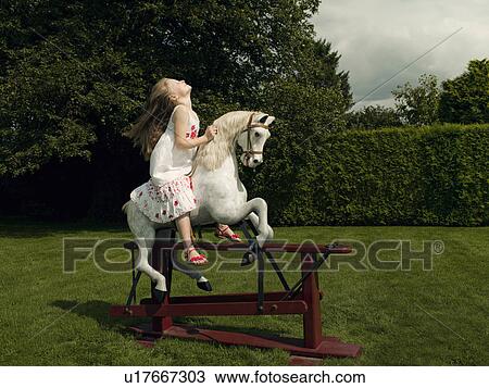 Stock Image - A young girl on a rocking horse. Fotosearch