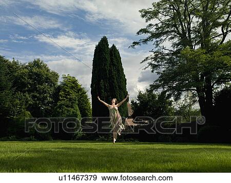 A young woman dancing in a garden View Large Photo Image Stock Photo - A young woman dancing in a garden. Fotosearch
