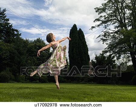 Stock Photo - A young woman dancing in a garden. Fotosearch